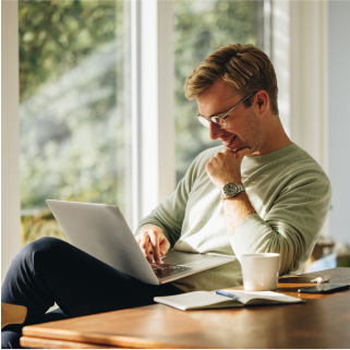 Photo of a man smiling at his laptop