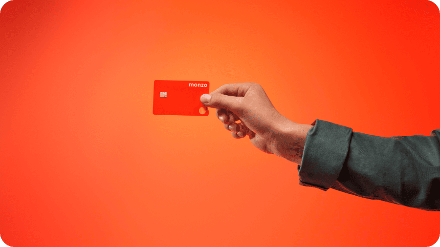 A hand holding a Monzo card.