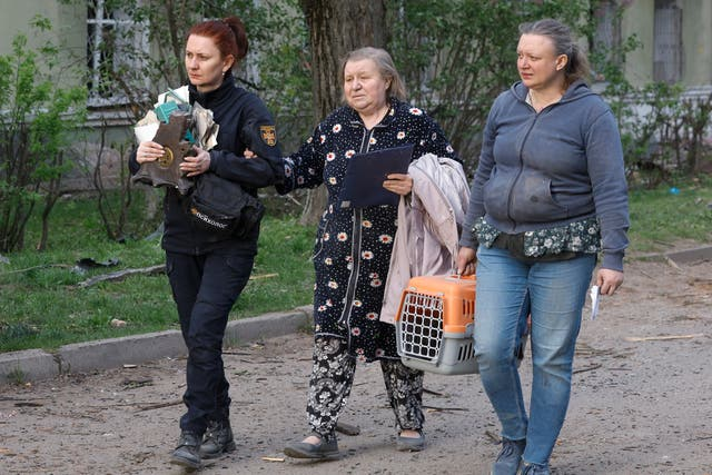 Ukrainian civilians walk with their belongings after an overnight strike in Kyiv killed at least a dozen civilians and injured 90 others