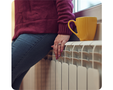 A person warming themselves against a radiator