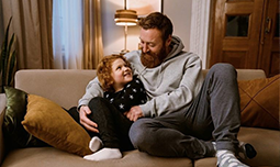 An adult with their child sat on a settee