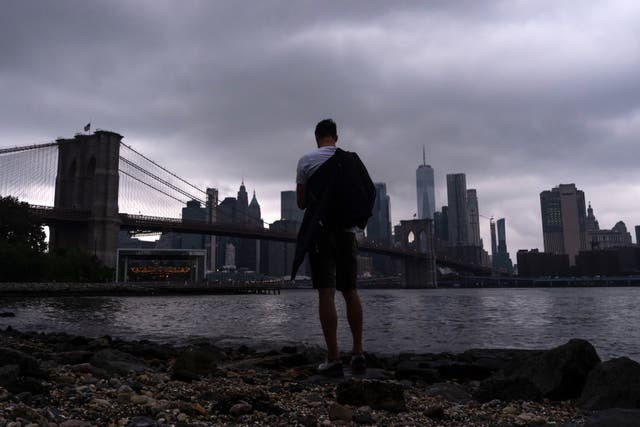 A man watches storms gather at the Brooklyn Bridge