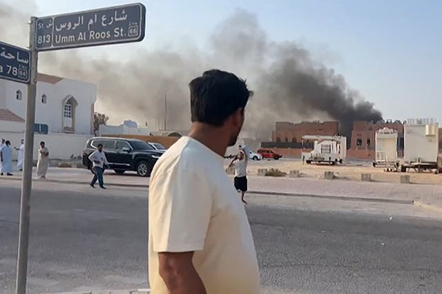 A man looks at a smoke plume rising after an Israeli strike on Doha, Qatar