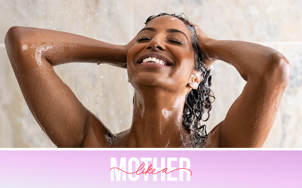 Enjoying a luxuriously warm shower, a mother smiles broadly as she rinses shampoo out of her hair.