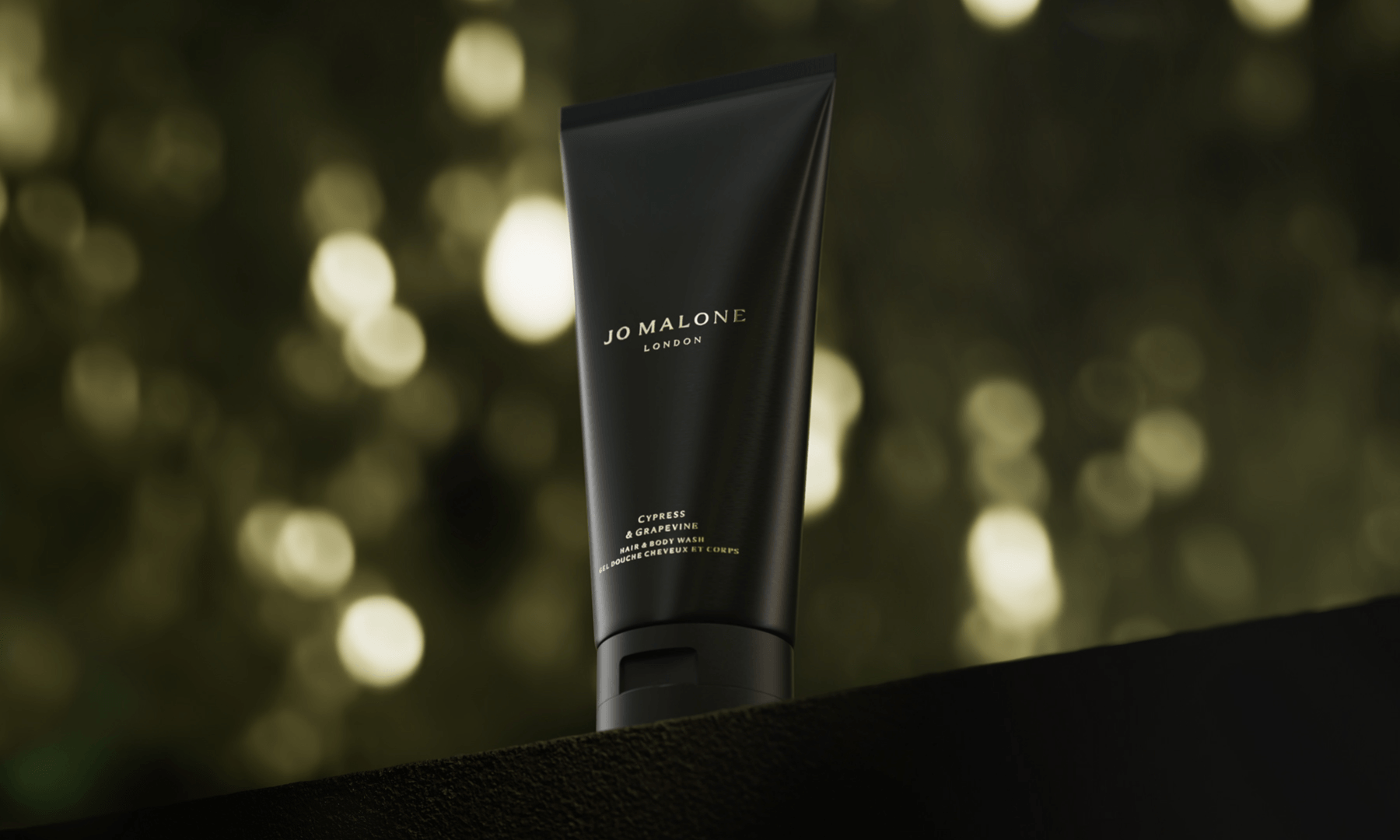 Cypress & Grapevine Hair & Body Wash against a softly blurred, warm bokeh background.