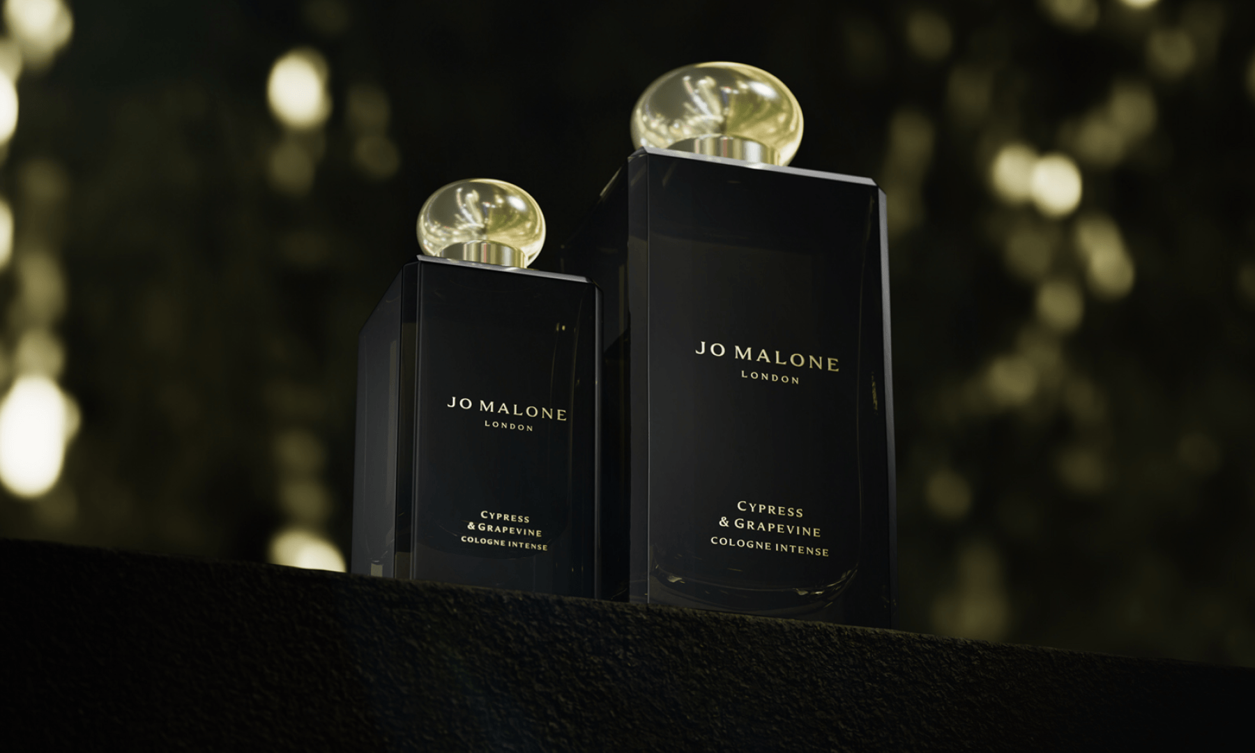 Two bottles of Cypress & Grapevine Cologne Intense against a softly blurred, warm bokeh background.