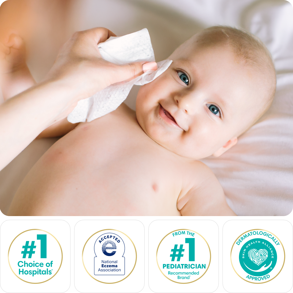 A mother’s hand uses a wipe to gently clean her smiling baby’s face.