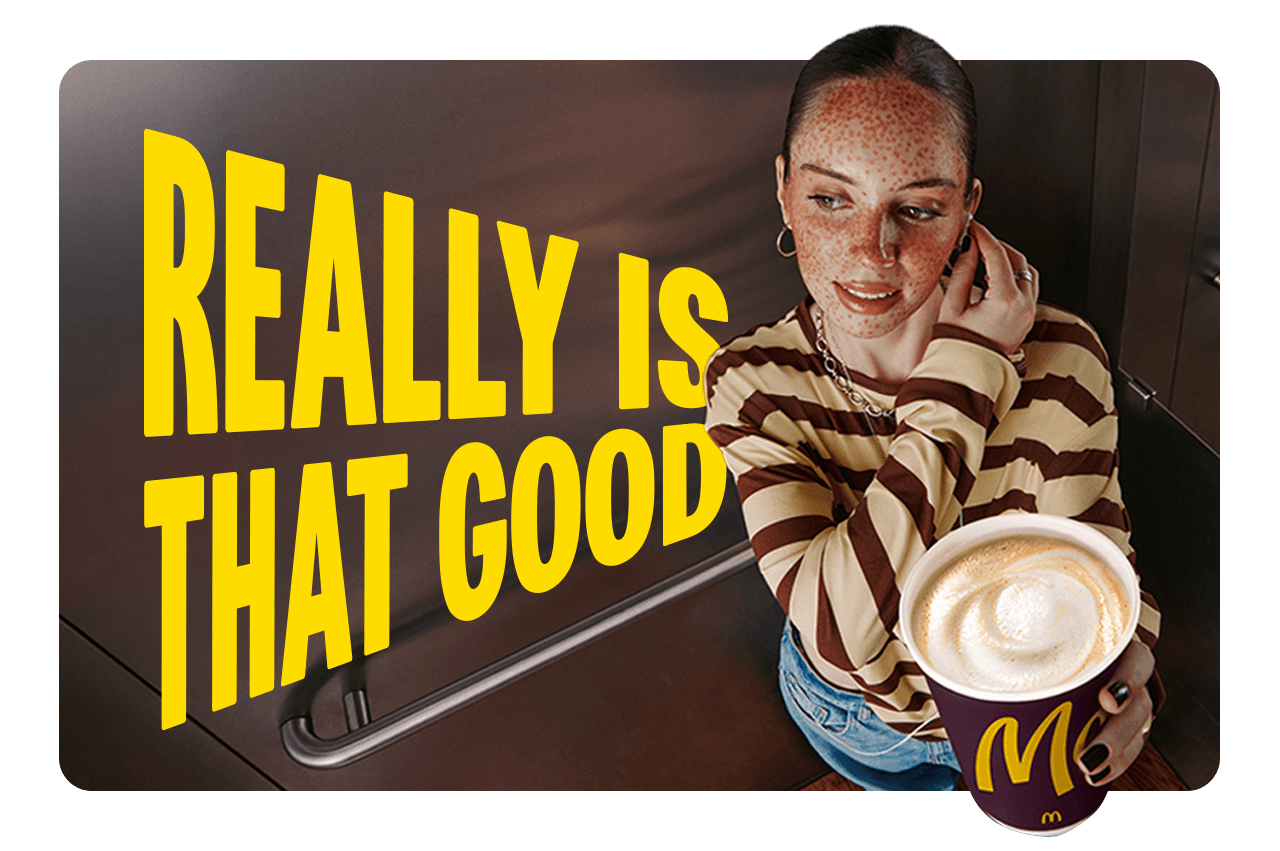 A woman standing in an elevator, holding a McCafe coffee. Text alongside her reads 'Really is that good'.