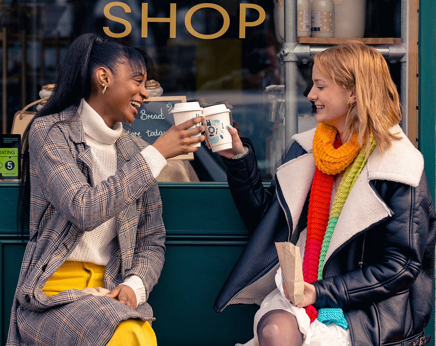 Two women smiling and cheersing coffee cups